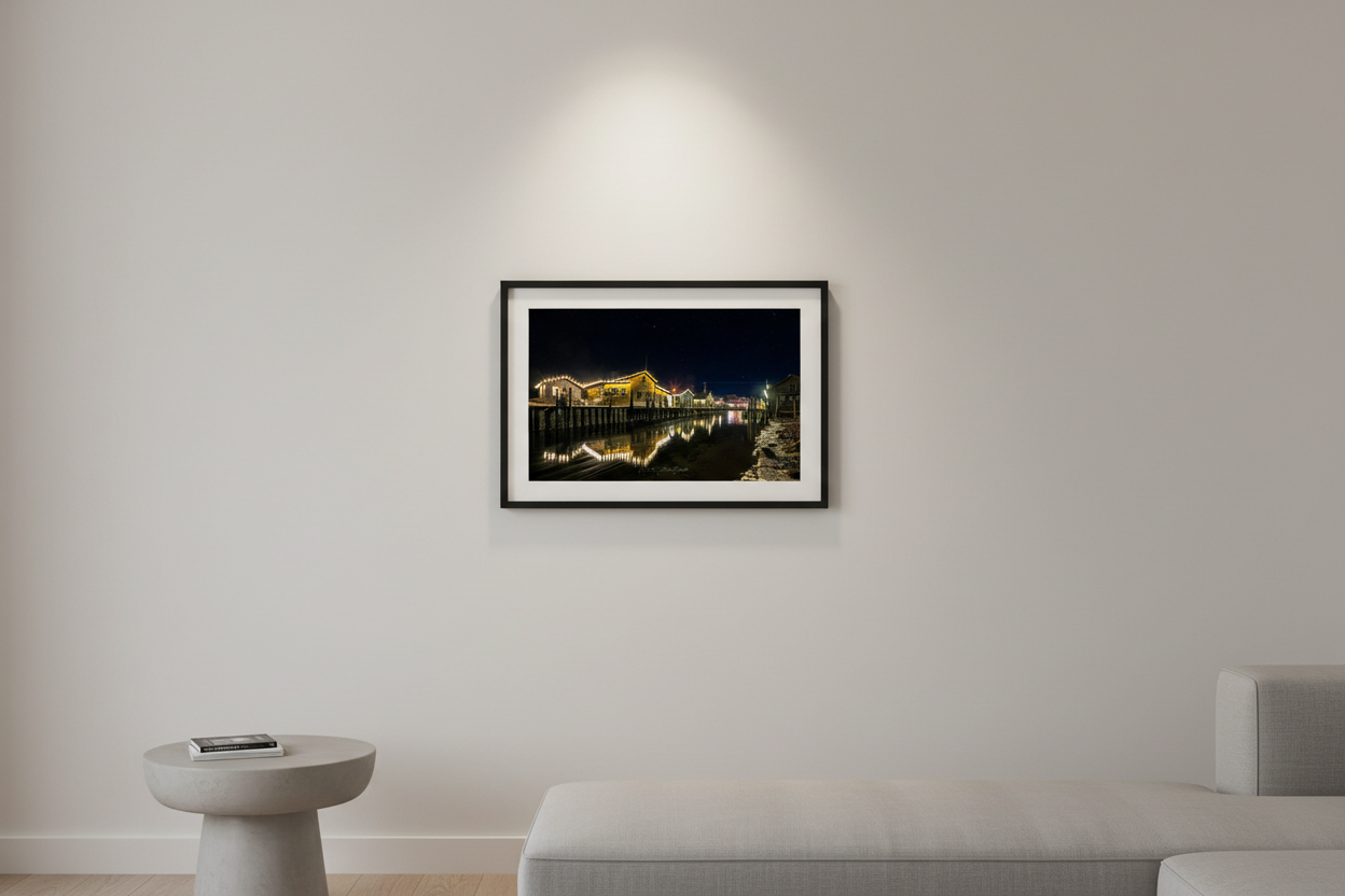 Small fine art print of illuminated Fishtown fishing shacks at night with Christmas lights reflecting on water displayed in modern living room